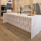 An open format kitchen with wood look tile on the floor and a marble island with random mosaic on the front of the island