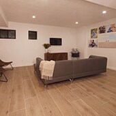 Basement family room with light colored wood look tile floor