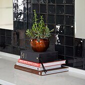 Close up of bathroom vanity with glossy black square ceramic tiles on the backsplash